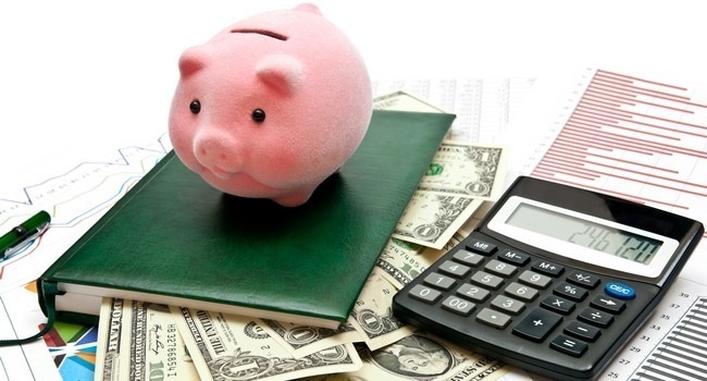 Piggy bank on office table with charts, money, calculatro and notebook
